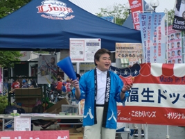 写真：福生ドッグを手にPRする市長